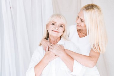 zarif sarışın olgun kızı sarılma ve kıdemli anne bakıyor