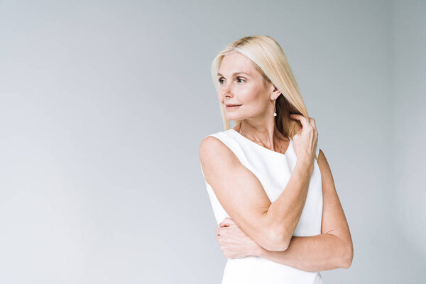 счастливая блондинка элегантная зрелая женщина, уединяющаяся на сером
