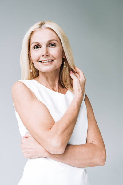 счастливая блондинка зрелого возраста смотрит на камеру изолированную от серого
