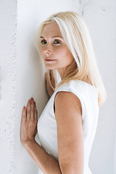 dreamy blonde mature woman near white wall