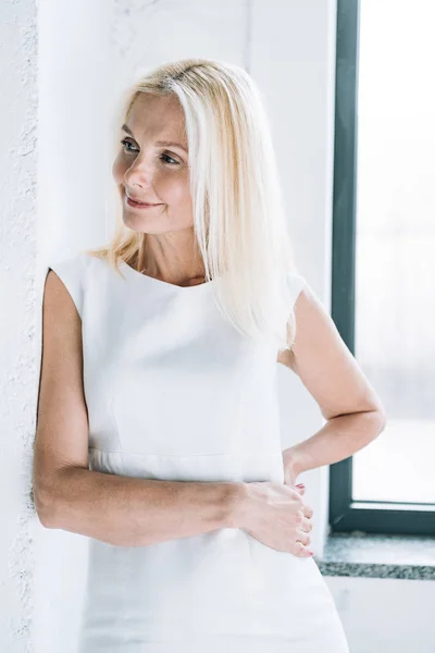 Lächelnde Blonde Reife Frau Der Nähe Weißer Wand Und Fenster — Stockfoto