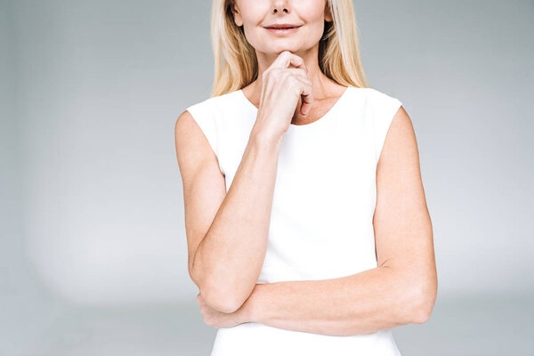 обрезанный вид улыбающейся блондинки зрелой женщины, изолированной на сером
