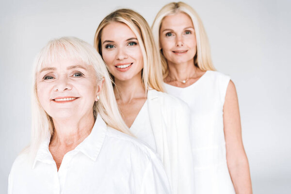 selective focus of attractive three generation blonde women isolated on grey