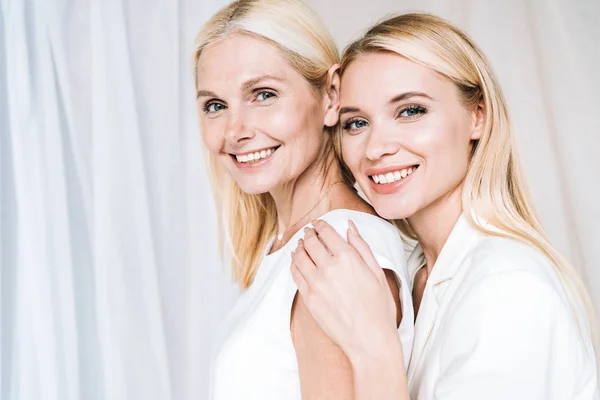 Smiling Elegant Blonde Daughter Gently Hugging Mature Mother — Stock Photo, Image