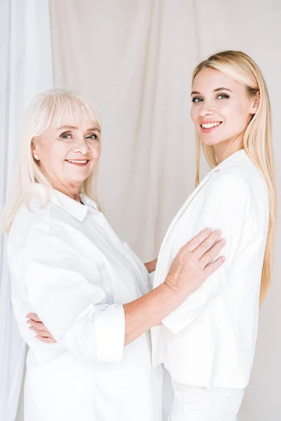 Smiling Blonde Grandmother Granddaughter Embracing Total White Outfits — Stock Photo, Image