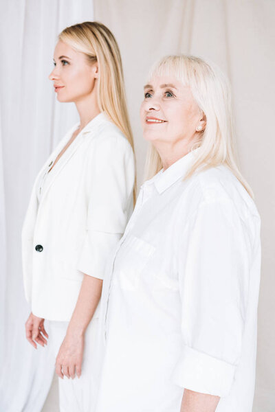 selective focus of blonde grandmother and granddaughter together in total white outfits