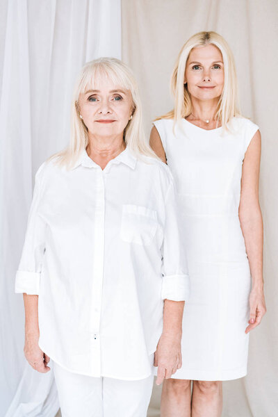 elegant blonde mature daughter and senior mother in total white outfits