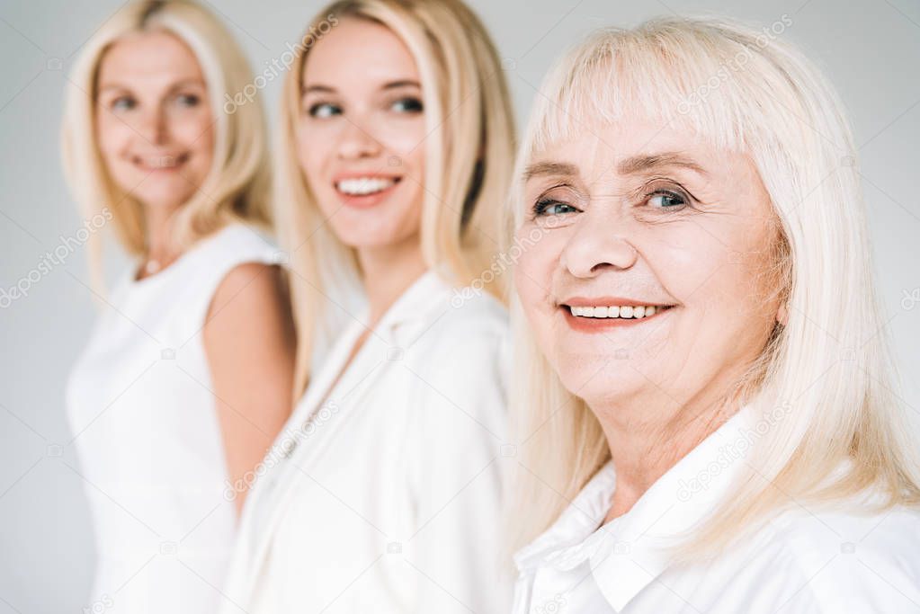 selective focus of three generation blonde women isolated on grey
