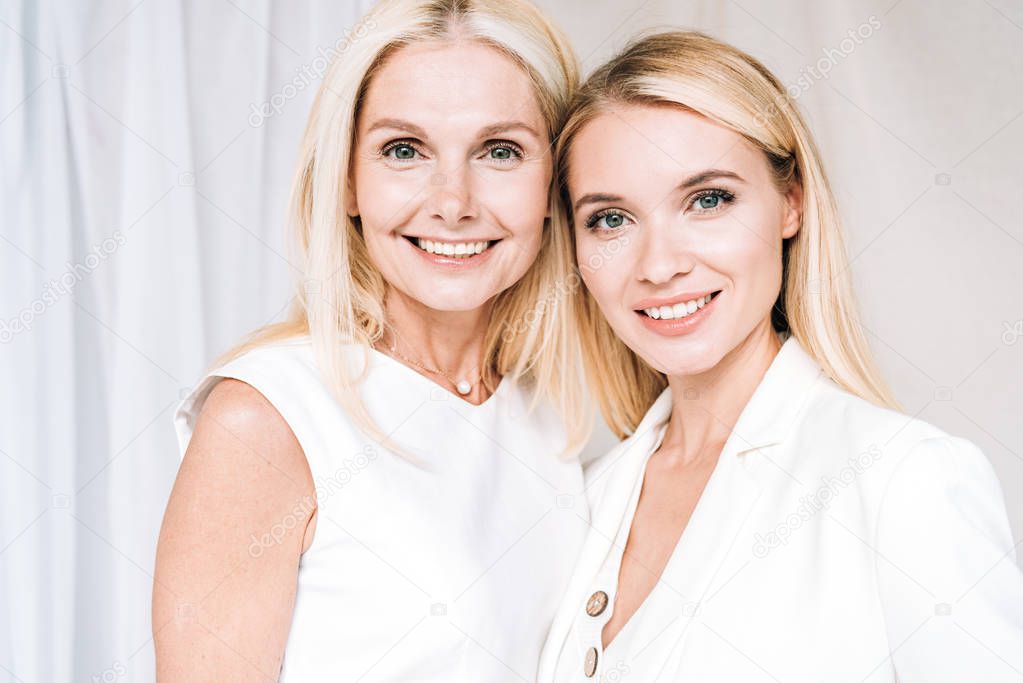 smiling blonde mother and daughter in total white outfits