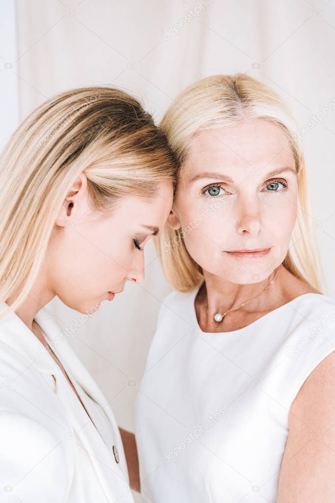 beautiful elegant blonde mother and daughter embracing on beige background