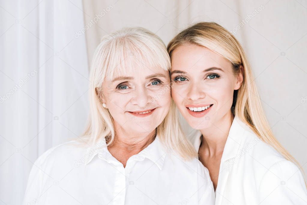 cheerful blonde grandmother and granddaughter together in total white outfits