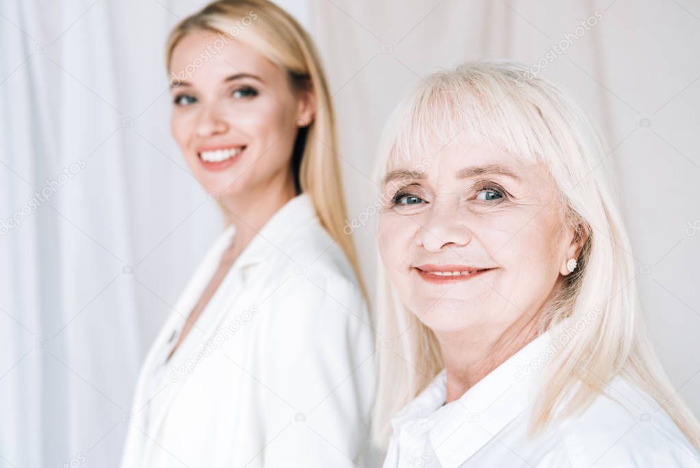 selective focus of smiling blonde grandmother and granddaughter