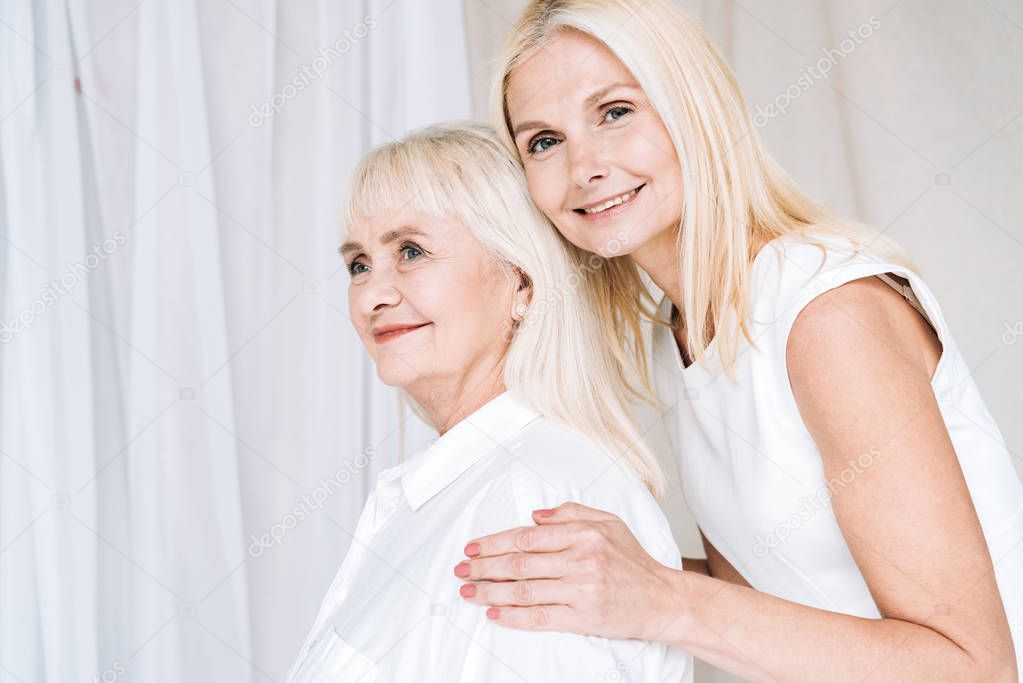 elegant blonde mature daughter embracing senior mother