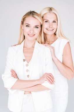 gülümseyen sarışın olgun anne gri izole toplam beyaz giysiler genç kızı sarılma