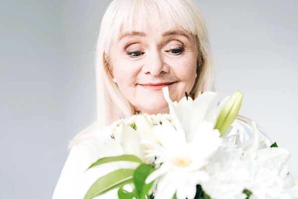 Усміхнена Старша Блондинка Білому Одязі Дивиться Квіти Ізольовані Сірому — стокове фото