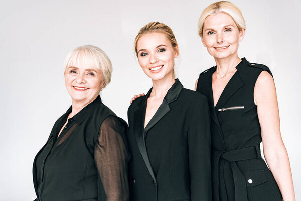 счастливые модные блондинки в трех поколениях в черных нарядах, изолированных от серых
