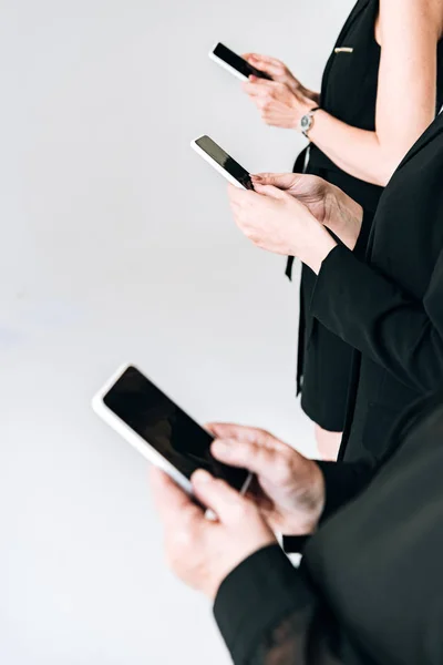 Vista Cortada Mulheres Negócios Roupas Pretas Totais Usando Smartphones Isolados — Fotografia de Stock
