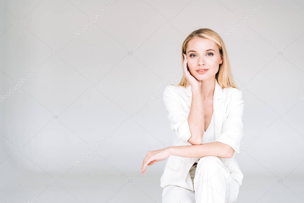 beautiful young blonde woman in total white outfit isolated on grey