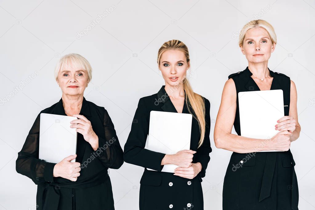 fashionable three-generation blonde businesswomen in total black outfits with blank boards isolated on grey