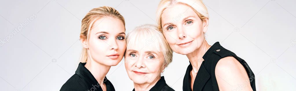 panoramic shot of three-generation blonde women in total black outfits isolated on grey