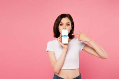Kiev, Ukrayna - 3 Temmuz 2019: pembe izole skype logosu ile akıllı telefon parmak ile işaret şok kız