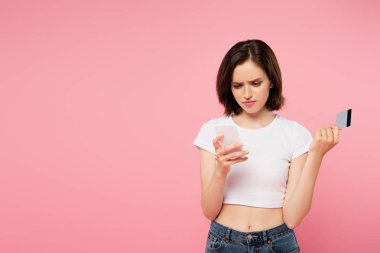 pembe izole akıllı telefon ve kredi kartı tutan karışık kız