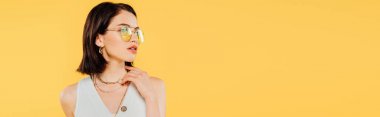 panoramic shot of elegant woman in sunglasses posing isolated on yellow clipart