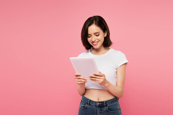 beautiful smiling girl using digital tablet isolated on pink