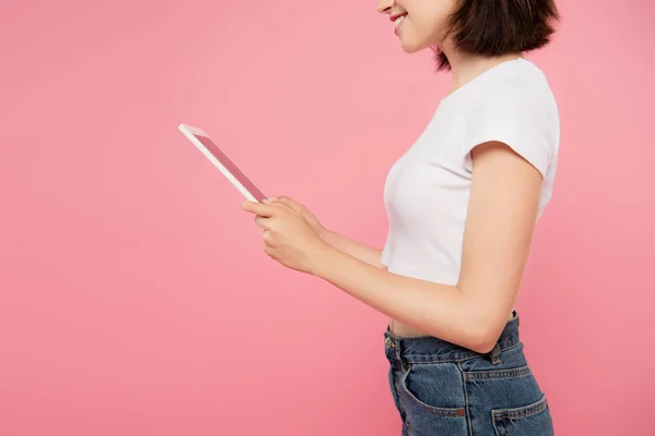 裁剪视图美丽的微笑的女孩使用数字平板电脑隔离在粉红色 — 图库照片