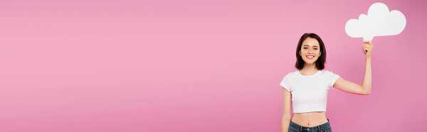 panoramic shot of smiling pretty girl holding blank white thought bubble isolated on pink