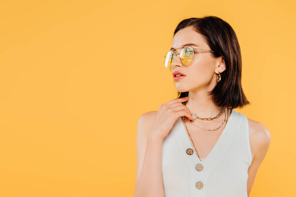 elegant woman in sunglasses posing isolated on yellow