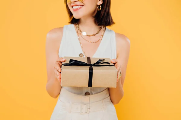 裁剪视图微笑优雅的女人拿着礼品盒隔离在黄色 — 图库照片