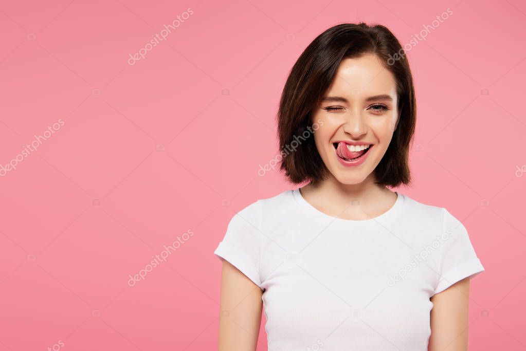 beautiful girl showing tongue and winking isolated on pink