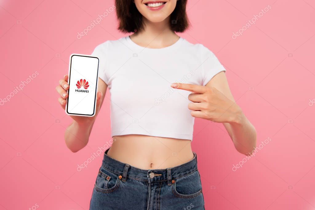 KYIV, UKRAINE - JULY 3, 2019: cropped view of girl pointing with finger at smartphone with huawei logo isolated on pink