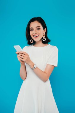 mavi izole akıllı telefon kullanarak elbise içinde gülümseyen zarif kadın