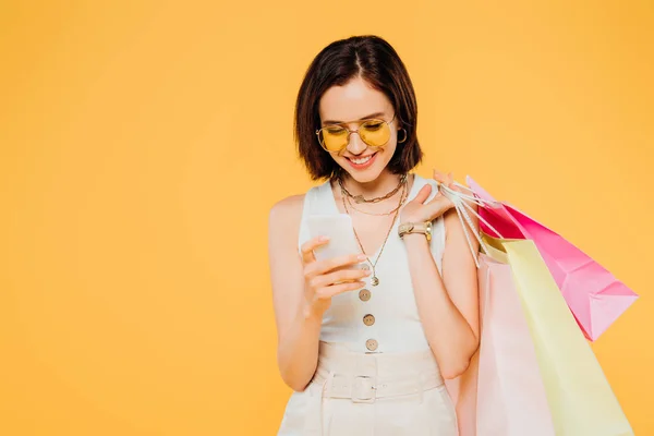 Happy Fashionable Girl Sunglasses Shopping Bags Using Smartphone Isolated Yellow — Stock Photo, Image