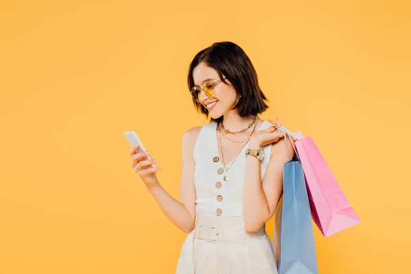 Leende Fashionabla Flicka Solglasögon Med Shoppingväskor Med Smartphone Isolerad Gult — Stockfoto