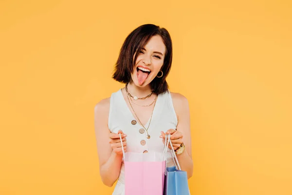 黄色で孤立した舌を示すショッピングバッグを持つファッショナブルな女の子 — ストック写真