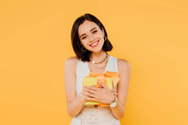 快乐微笑的女孩拿着礼品盒隔离在黄色 — 图库照片