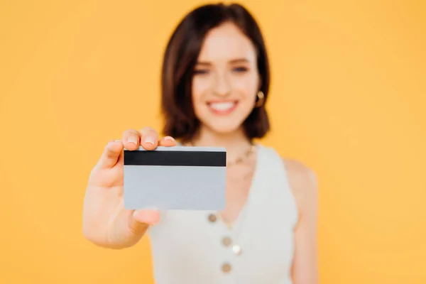 黄色に隔離されたクレジットカードを保持している笑顔のエレガントな女の子の選択的な焦点 — ストック写真