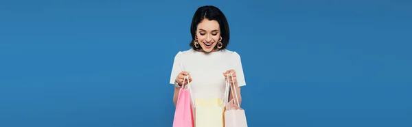 Tiro Panorámico Mujer Elegante Excitada Vestido Sosteniendo Bolsas Aisladas Azul —  Fotos de Stock