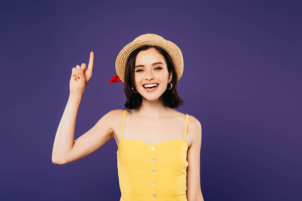 smiling girl in straw hat showing idea gesture isolated on purple