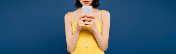 обрезанный вид девушки с помощью смартфона изолированы на синий
