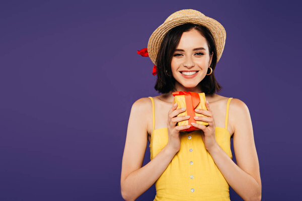 smiling girl in straw hat holding present isolated on purple