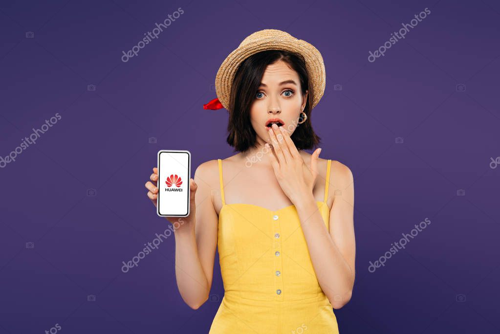 KYIV, UKRAINE - JULY 3, 2019: girl in straw hat showing idea gesture and holding smartphone with Huawei logo isolated on purple