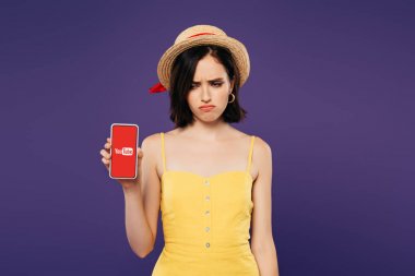 Kiev, Ukrayna - Temmuz 3, 2019: mor izole youtube uygulaması ile akıllı telefon tutan hasır şapka üzgün güzel kız 