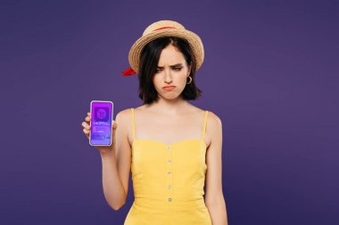 mor izole online alışveriş uygulaması ile akıllı telefon tutan hasır şapka üzgün güzel kız 