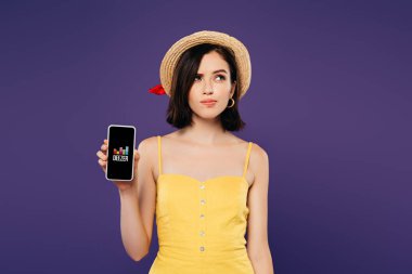 Kiev, Ukrayna - 3 Temmuz 2019: mor izole deezer uygulaması ile akıllı telefon tutan hasır şapka rüya gibi güzel kız 