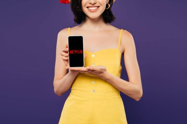 Kiev, Ukrayna - 3 Temmuz 2019: mor izole netflix uygulaması ile akıllı telefon tutan gülümseyen kız kırpılmış görünümü 