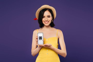 Kiev, Ukrayna - 3 Temmuz 2019: mor izole uber uygulaması ile akıllı telefon tutan hasır şapka güzel kız gülümseyen 